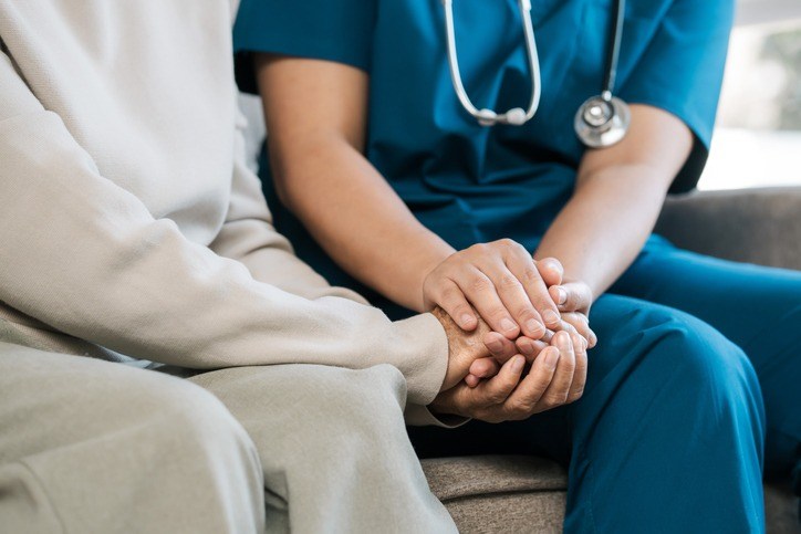 A nurse comforts an elderly woman by holding her hand reflecting kindness in Shreveport, LA