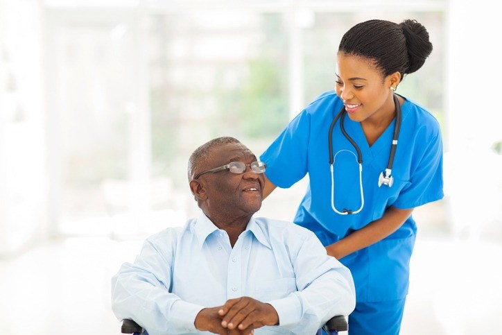 A nurse assists an elderly man in a wheelchair at a long-term care facility in Shreveport, LA