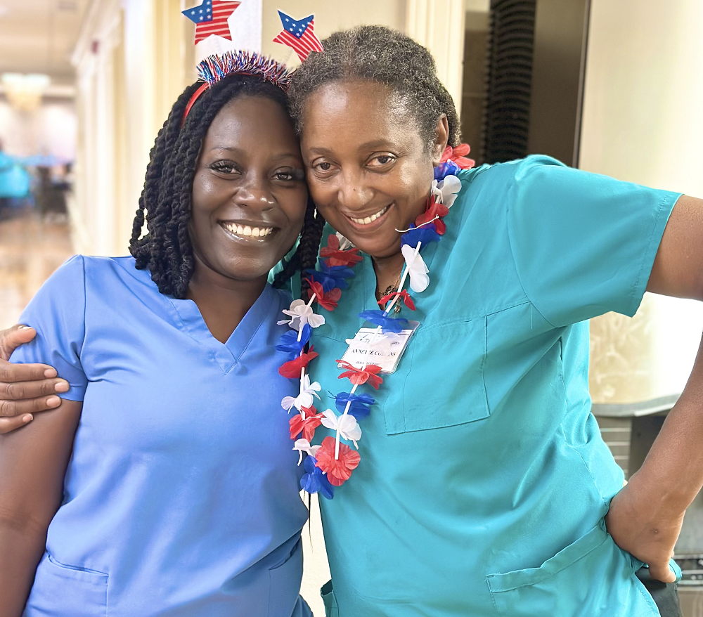Two female staff members embrace in hallway