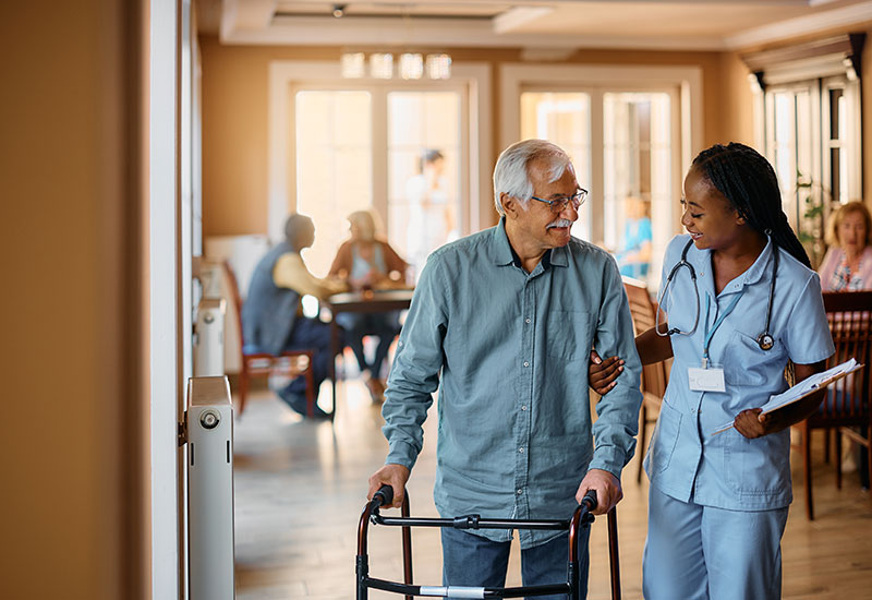 Nurse helps elderly man walk back to his room at a nursing facility in Shreveport