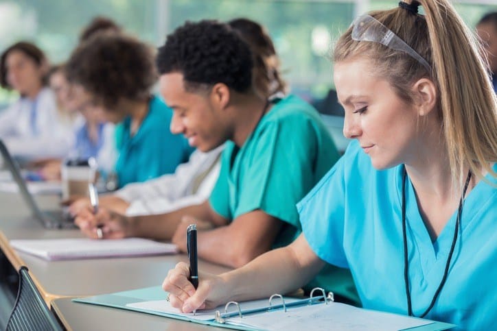 A group of nurses gathered at a table, engaged in writing