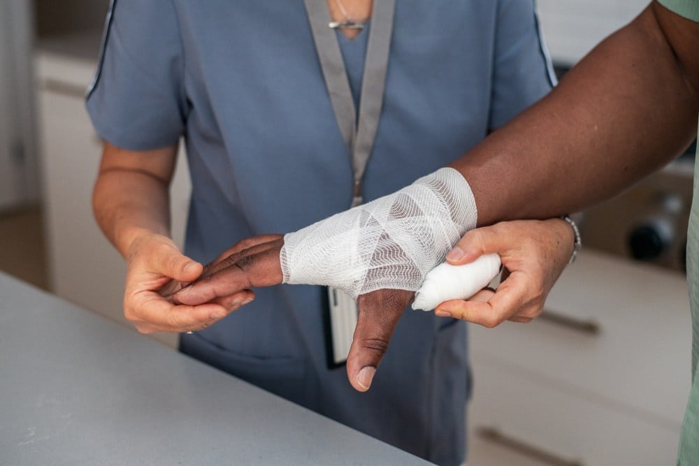 A nurse bandages a wound on a patient's hand at a skilled nursing facility